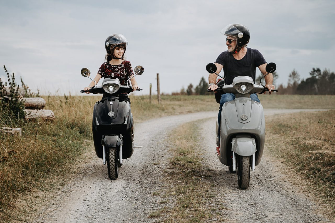 Vater-Tochter-Gespann auf den Rollern auf einem Feldweg